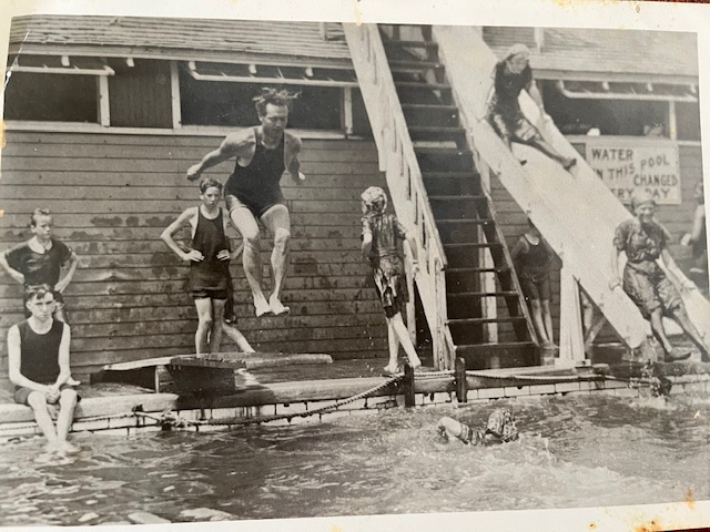 A man jumping into the avon pool while others go down the slide
